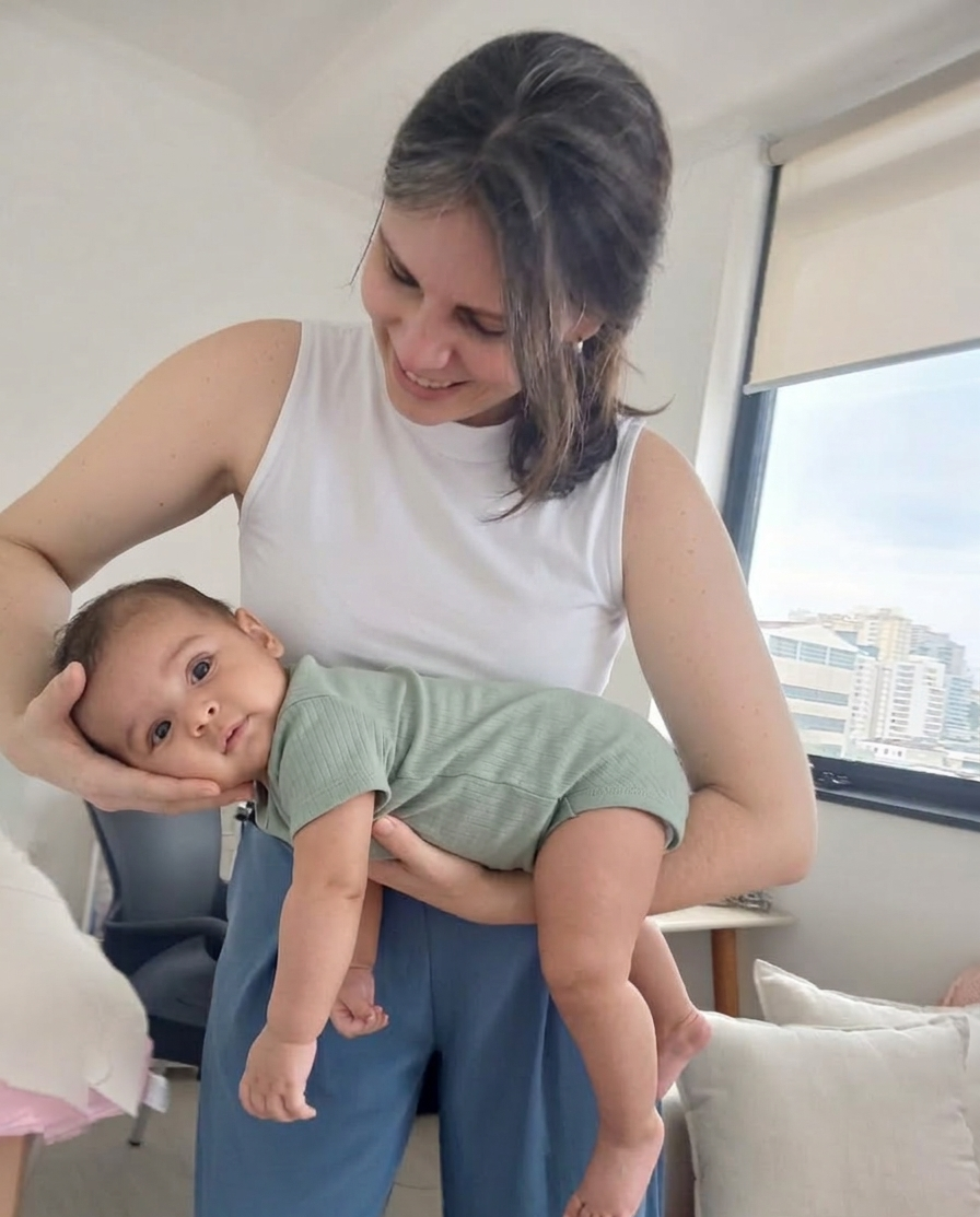 Dra. Natália Folco acolhendo um bebê no colo junto à janela